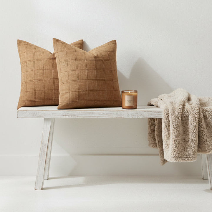 Two brown checkered pillows on a light-colored sofa.