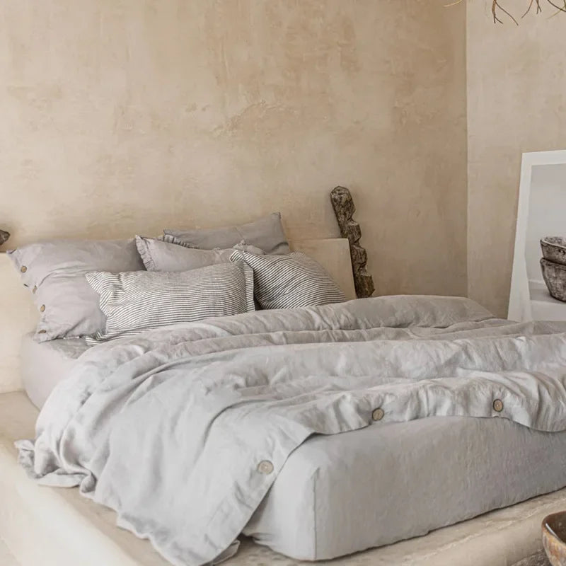 Neatly made bed with light gray bedding in a bedroom setting.
