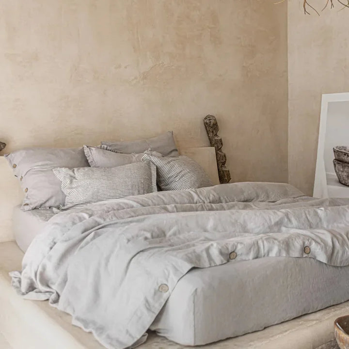 Neatly made bed with light gray bedding in a bedroom setting.